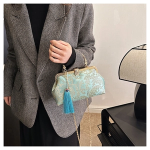 Détail du sac coquille en brocart vert menthe avec broderie dorée et pompon bleu