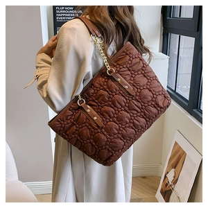 Dettaglio borsa trapuntata marrone con texture satinata e catena dorata