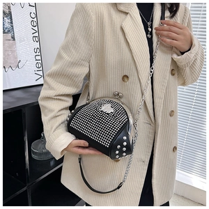 Detail of vintage shell bag with rhinestones and metal rivets on model in beige blazer