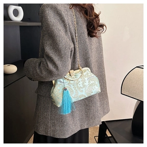 Détail du sac brodé en forme de coquille avec motifs floraux, glands et chaîne