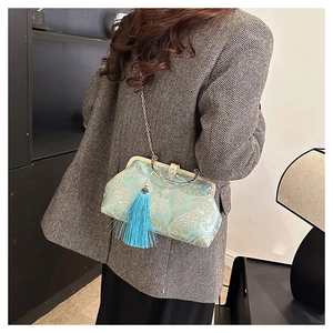 Detail of light blue embroidered shell bag with golden tassel and metal chain