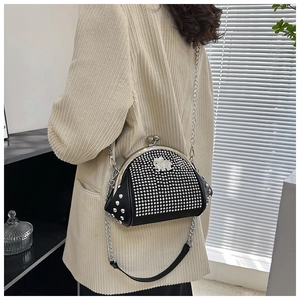 Detail of a black rhinestone shell bag with elephant charm and silver chain strap