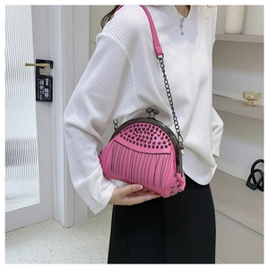 Detail der rosa Muschel-Tasche mit schwarzen Nieten und Metallfransen an einem Rahmen