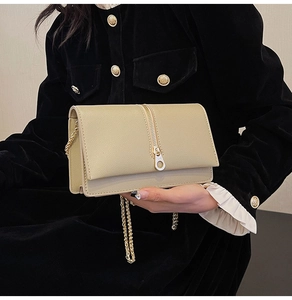 Detail of beige pebbled leather bag with gold chain strap and stylish vertical zippers