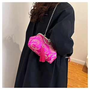 Macro view of rose red silk shell bag featuring gold floral embroidery and long tassel