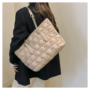 Dettaglio della borsa tote beige trapuntata con texture a bolle e catena dorata