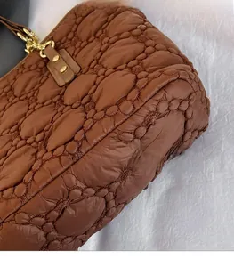 Dettaglio borsa trapuntata marrone con texture in nylon e chiusure in metallo oro