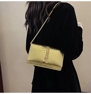 Detail of gold snake embossed shoulder bag with chic chain strap on model