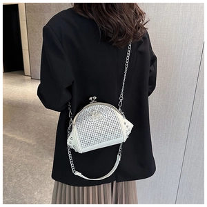Macro shot of a white rhinestone shell bag with silver chain worn on a black blazer