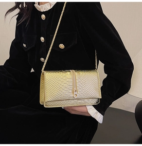 Detail of gold snake-pattern chain bag with vintage zipper ring and metal luster
