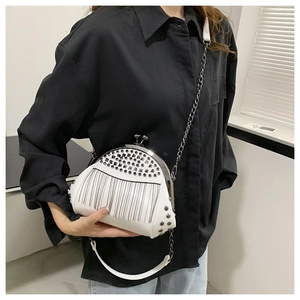 Detailansicht der weißen Ledertasche mit silbernen Nieten und Metallkettenfransen