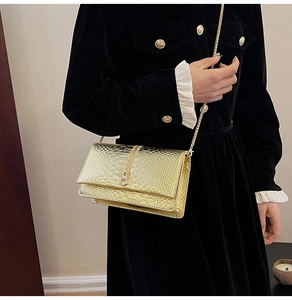 Detail of gold crocodile embossed shoulder bag with chain strap and decorative zipper