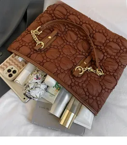 Interno spazioso della borsa trapuntata con ombrello, libri e vari prodotti cosmetici