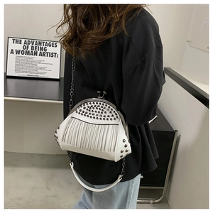 Detailansicht einer weißen Muscheltasche mit Silbernieten und Metallkettenfransen