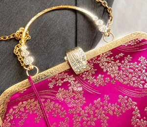 Dettaglio della chiusura vintage dorata con strass su borsa ricamata floreale rosa