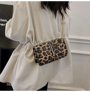 Detail of leopard print crossbody bag with gold chain strap shown on model shoulder