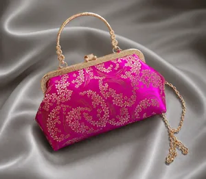 Dettaglio del ricamo in raso fucsia con motivi floreali dorati su una borsa a mano