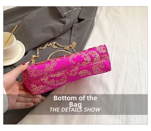 Detail showing the bottom of the fuchsia satin clutch with intricate gold floral embroidery