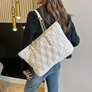 Borsa tote bianca trapuntata con catena dorata indossata da una modella in un interno