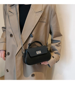 Detail of minimalist black crossbody bag with silver chain strap and metal swivel lock