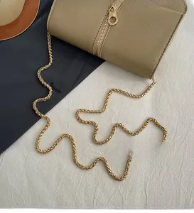 Detail of smooth gold chain strap and khaki lychee grain leather on a crossbody bag