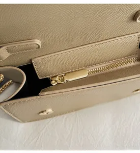 Detail view of smooth golden metal zipper and magnetic closure on beige pebbled leather bag
