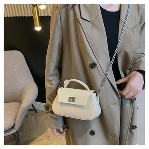 Detail of cream matte leather crossbody bag featuring silver chain strap and metal lock