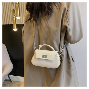 Chic beige leather handbag with silver twist lock shown on a khaki trench coat model