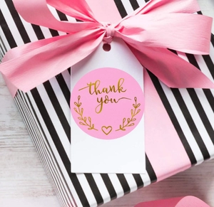 Pink round thank you stickers with gold foil hearts on a gift box packaging label