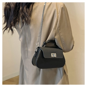 Detailed shot of a black matte crossbody bag with silver chain and metal twist lock