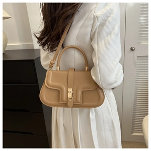 Détail du sac à bandoulière camel avec boucle dorée sur une tenue blanche