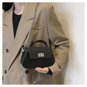 Detail of crossbody bag featuring silver turn-lock closure and elegant metal chain strap