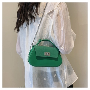 Detail of green crossbody bag with silver twist lock and knotted handle on model