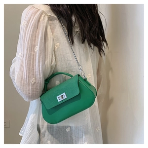 Detail of vibrant green chain crossbody bag with woven handle shown on model