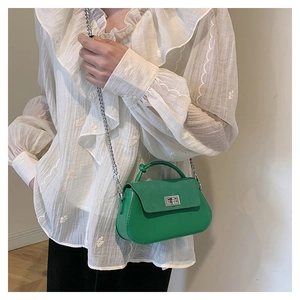 Close-up of green crossbody bag with silver chain strap and metal lock closure