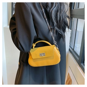 Detail of ginger yellow crossbody bag with metal chain and suede texture on black blazer