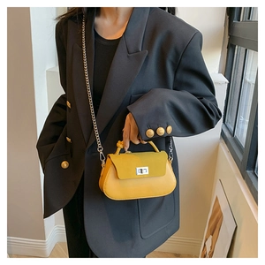 Detail of yellow patchwork handbag featuring a silver twist lock and metal chain strap