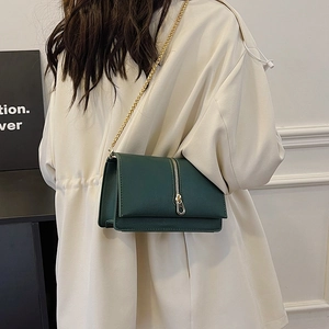 Minimalist dark green crossbody bag with gold chain strap and vertical zipper detail