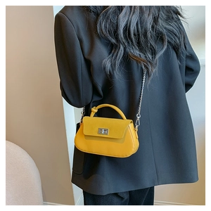 Modern yellow leather crossbody bag with chain strap shown on a model's side view