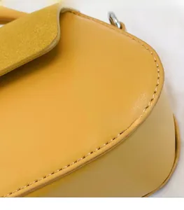 Detail of yellow leather handbag showing fine stitching and silver metal ring hardware