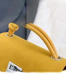 Detail of yellow matte leather handbag with knotted handle and silver twist lock