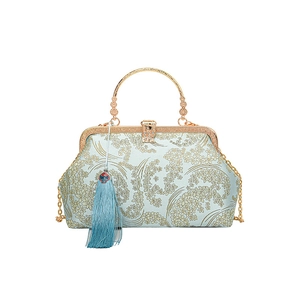 Sac coquille bleu avec broderie florale, poignée dorée et pompon décoratif frangé