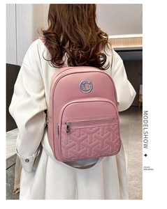 Rear view of a stylish pink quilted backpack with a metal logo on a model in white coat
