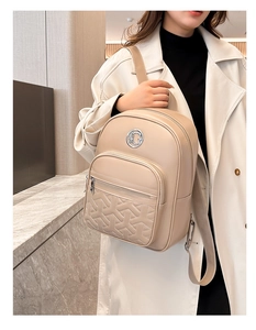 Close-up of beige leather backpack with geometric Y-shaped stitching and metal logo