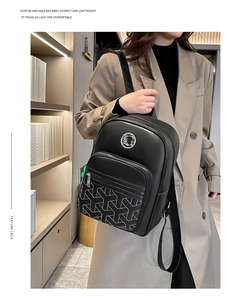 Detail of black leather backpack featuring geometric stitching and metallic logo buckle