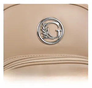 Macro shot of silver metal logo emblem and texture on beige synthetic leather bag