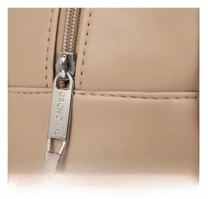Close-up of premium beige leather texture and smooth metal zipper with brand engraving
