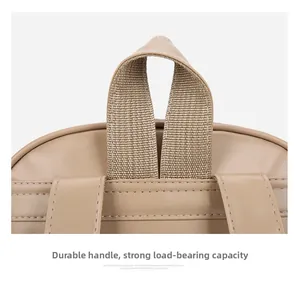Detailed close-up of durable reinforced top handle and shoulder strap stitching on beige backpack