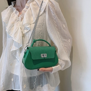 Green crossbody bag with matte flap and silver chain strap shown on model outdoors