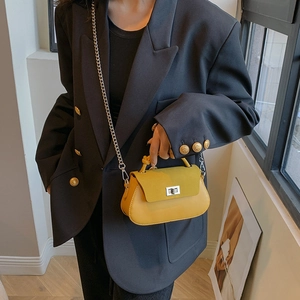 Yellow crossbody bag with silver chain and suede flap detail on a black blazer outfit